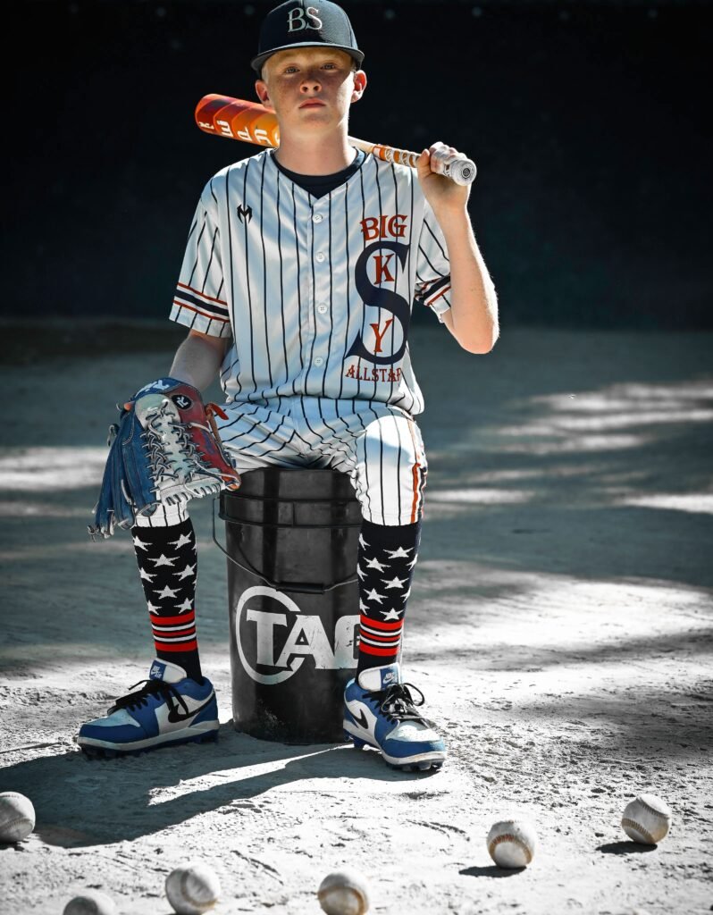Little League Baseball player posing in uniform with his bat and glove.