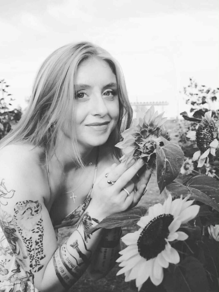 black and white photography of a young woman in a sundress in a garden with sunflowers.