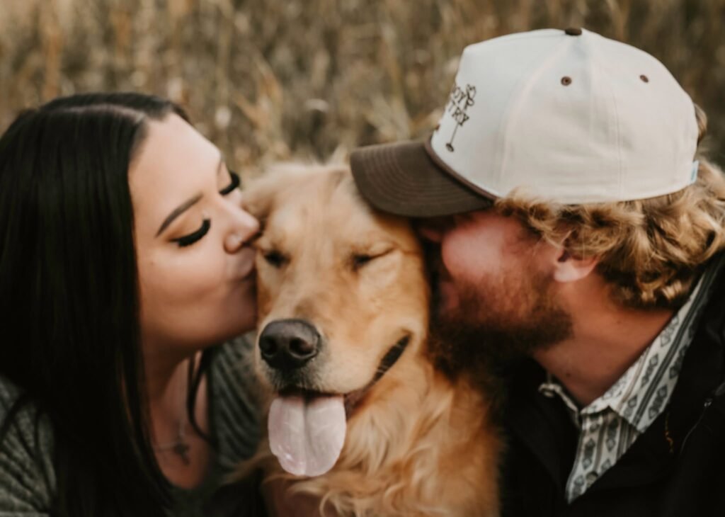 a young couple kissing their dog.