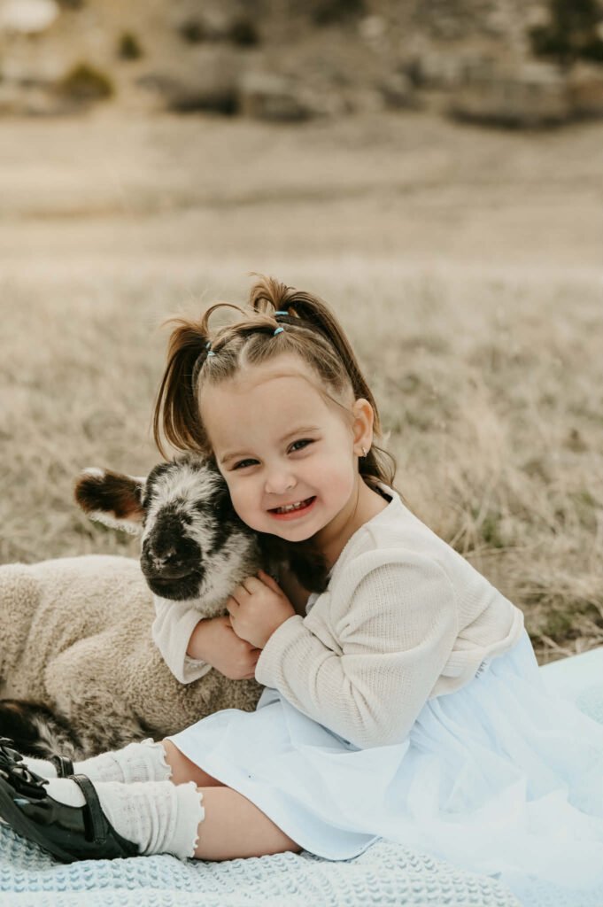 A little girl with a black-and-white faced lamb.