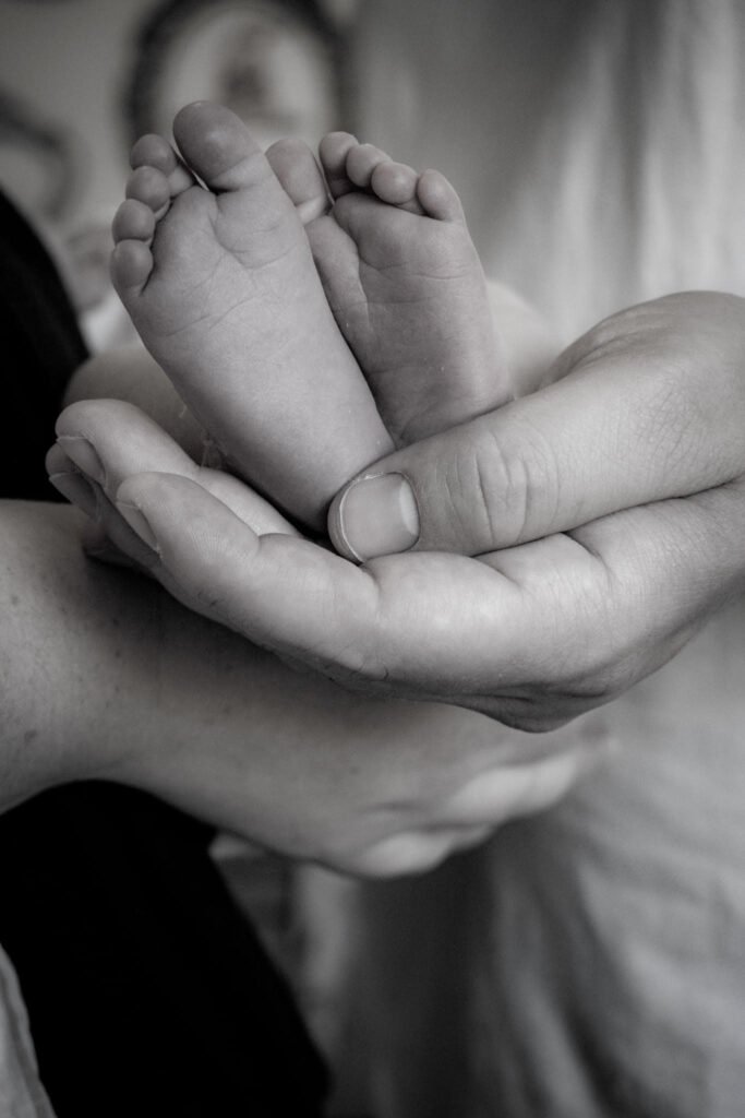 Black and white image of a newborn baby's feet cradled in her father's hand.
