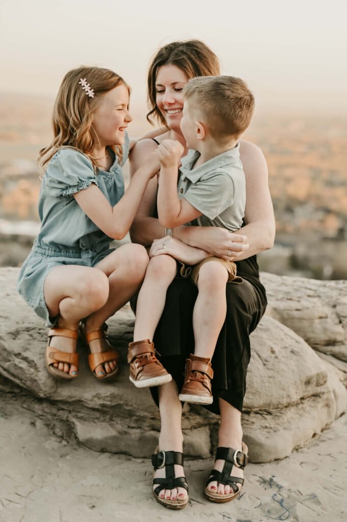 young mother with a little girl and a very young little boy sitting on a rock.